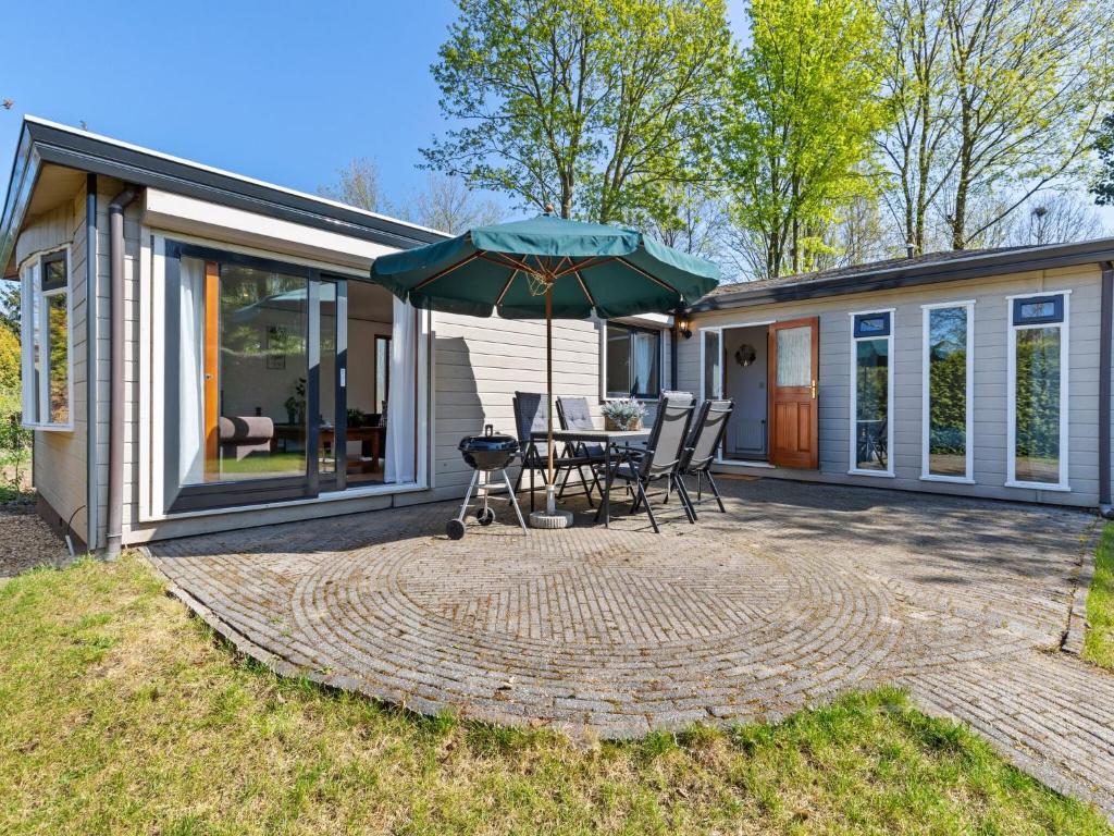 un patio con mesa y sombrilla en Modern Chalet in Garderen with Private Garden en Garderen
