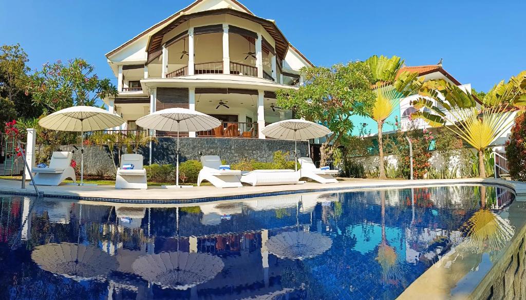 una casa con piscina con sillas y sombrillas en Villa Lilly Sea View Pool Villa, en Umeanyar
