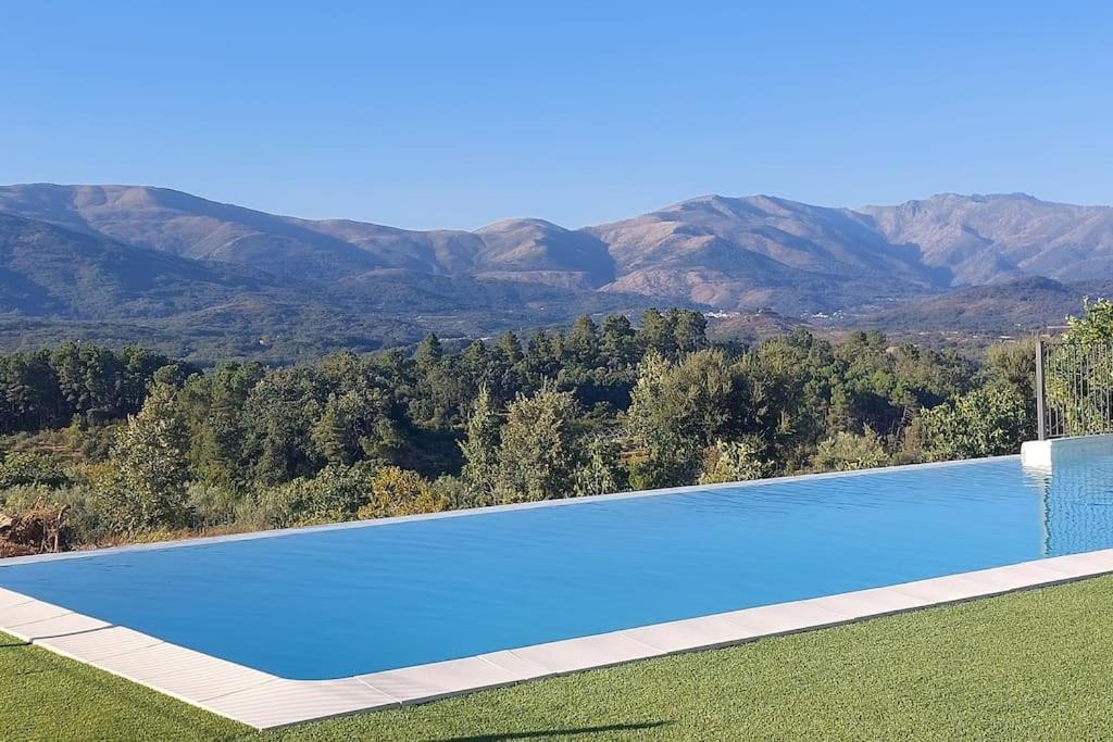a large blue swimming pool with mountains in the background at Casa rural Atalanta de la Vera in Jaraiz de la Vera