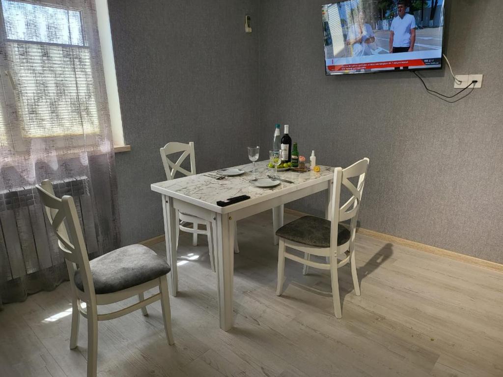 a white table with chairs and a tv on a wall at 15минут до центра Баку in Xirdalan