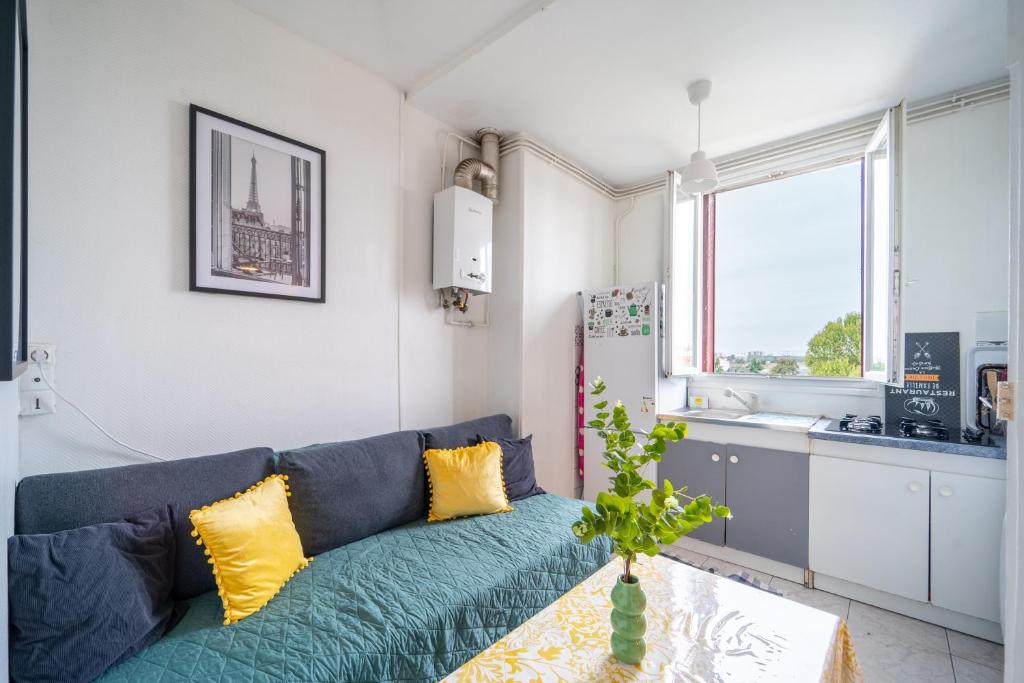 Una sala de estar con un sofá azul y una cocina. en L'Évasion Aulnaysienne - Appt pour 4, en Aulnay-sous-Bois