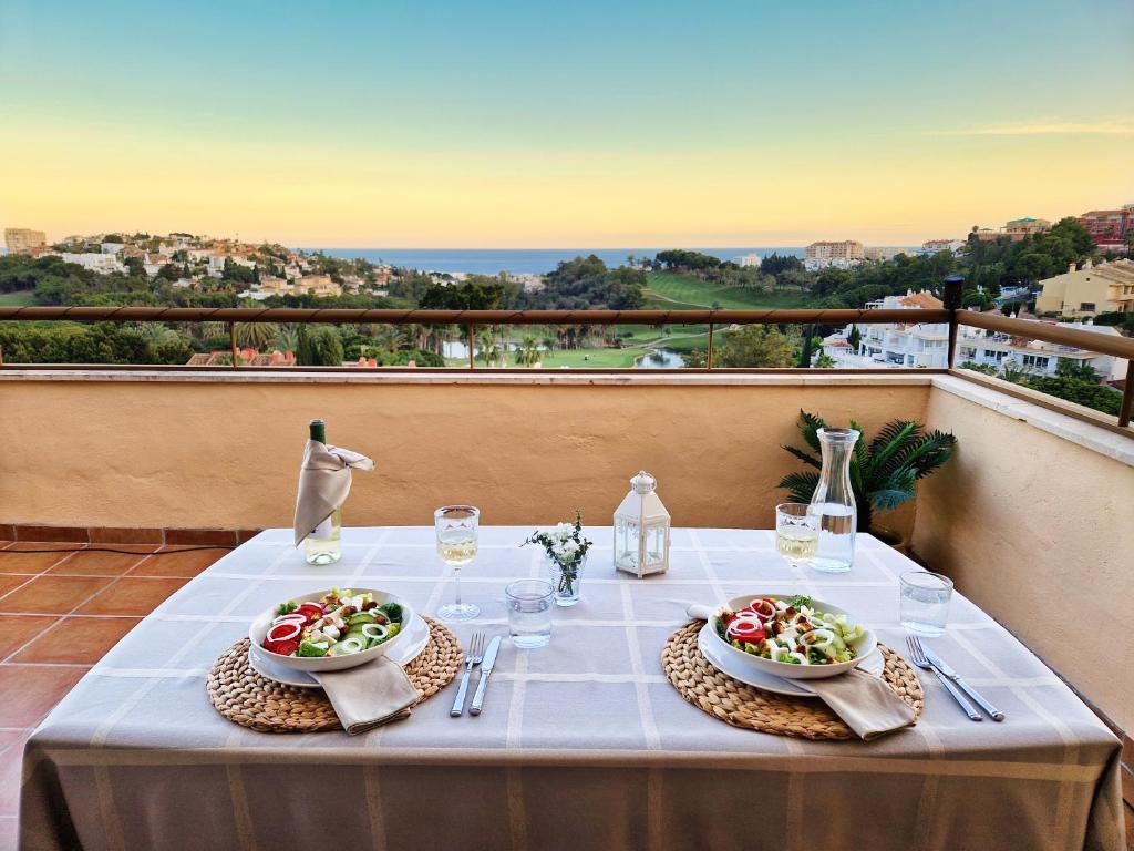 a table with two plates of food on a balcony at Penthouse Benalvistas Torregolf Seaview in Benalmádena