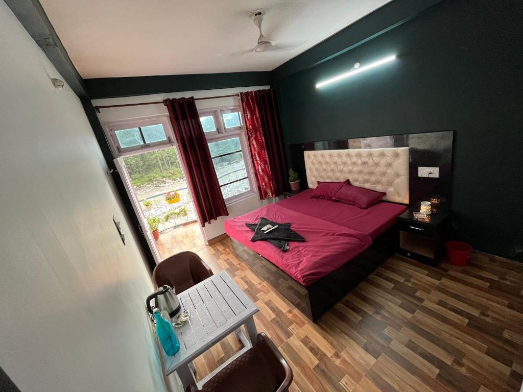 a bedroom with a red bed and a window at Shanti Cafe & Hostels in Kasol
