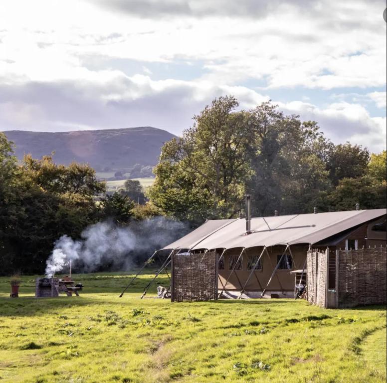 a large building in a field with smoke behind it at Seven Hills Hideaway - Blorenge in Llanvetherine