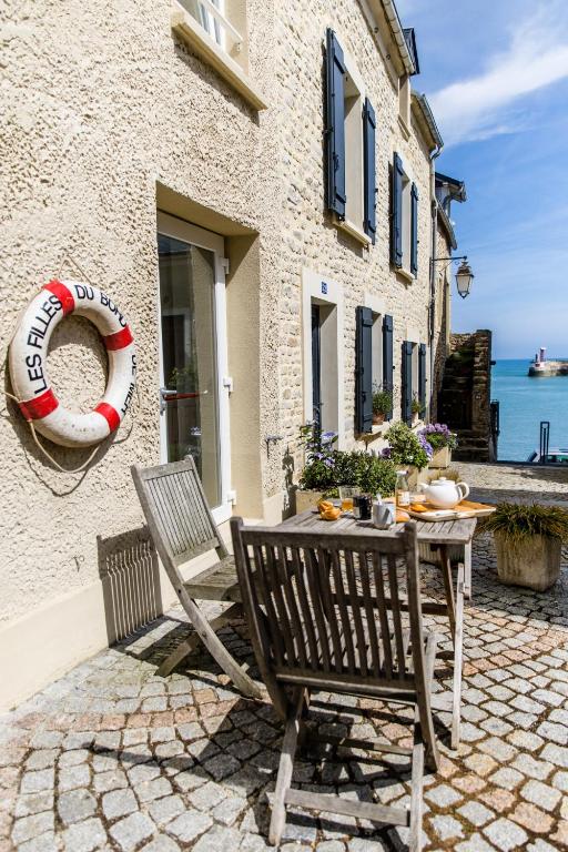 un patio avec une table et des chaises et l'océan dans l'établissement Mer nature, appartement spacieux by Les Filles du Bord de Mer, petite terrasse vue mer, à Port-en-Bessin-Huppain