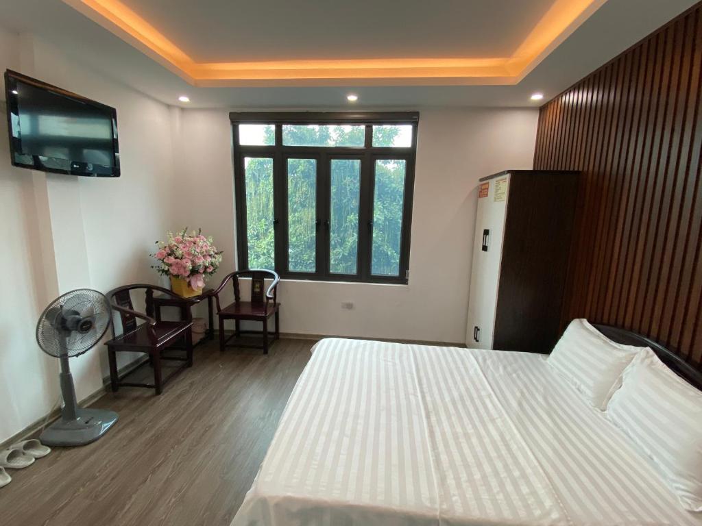 a bedroom with a bed and a tv and a table at Joy Nibi Guest House in Ninh Binh