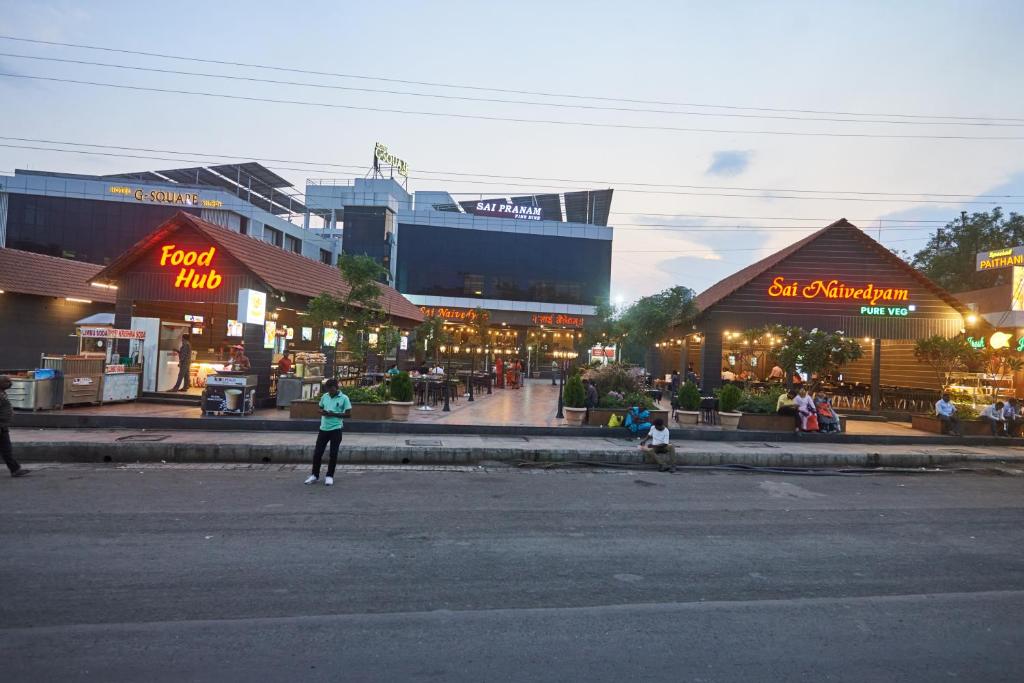 a woman is standing in the middle of a street at Hotel G-Square - Shirdi in Shirdi