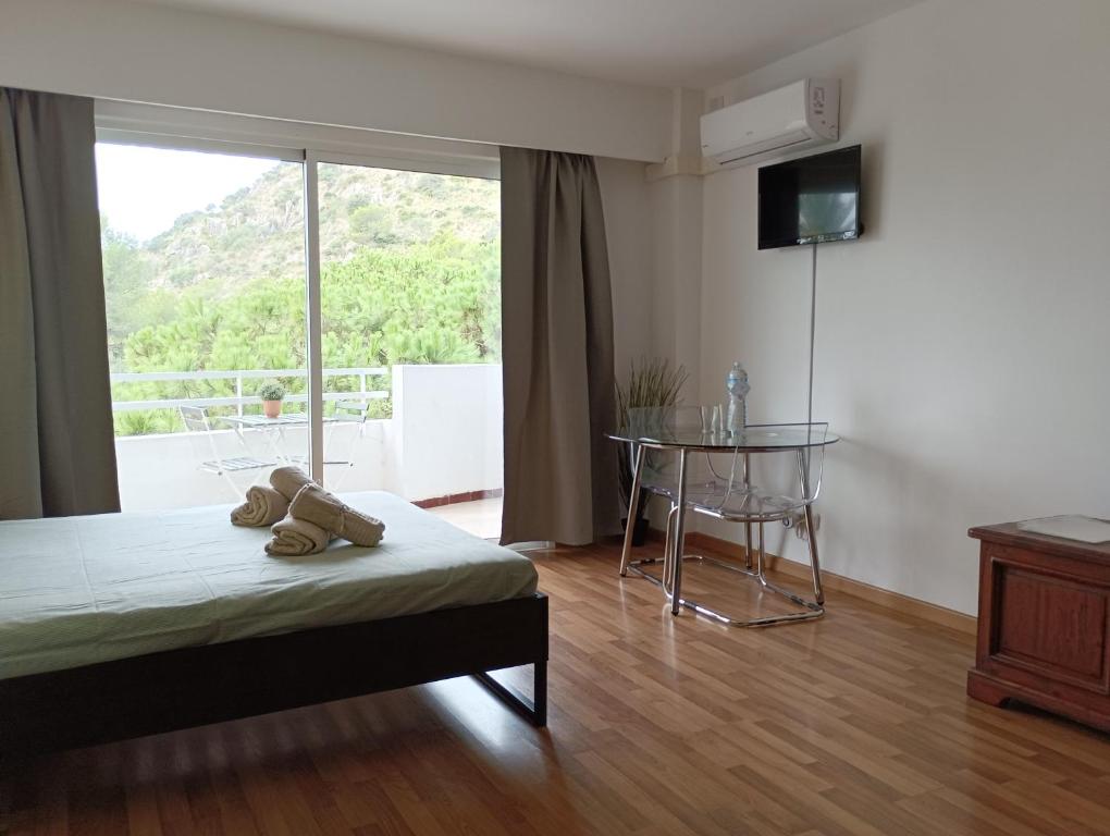 een slaapkamer met een bed, een tafel en een raam bij Piso moderno con piscina Siesta 2 in Port d'Alcudia