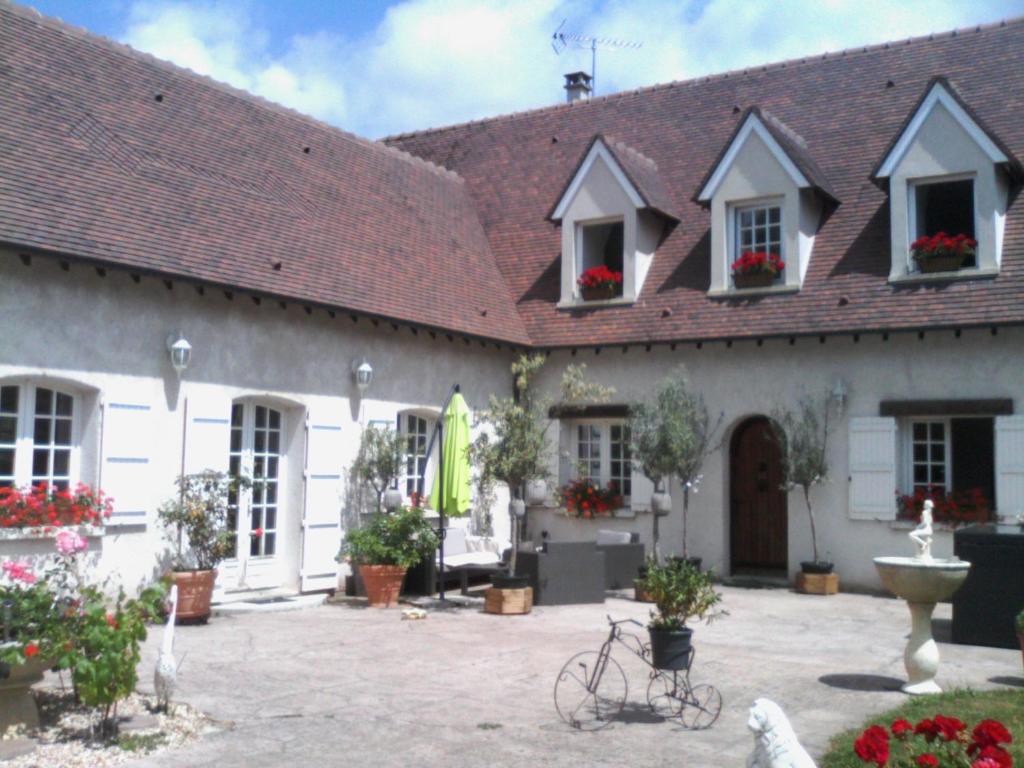 a large white building with flowers in a courtyard at Le Relais De Dalibray in Seraincourt