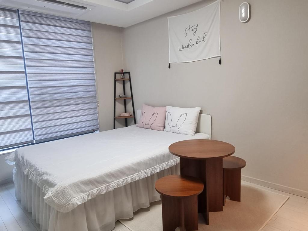 una piccola camera con un letto e due tavoli di Yolo House a Daegu