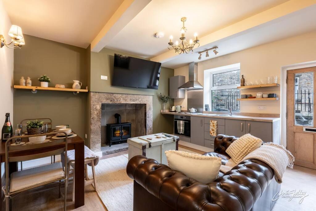 a living room with a couch and a table and a fireplace at Cosy Cottage in Heart of Glossop in Glossop
