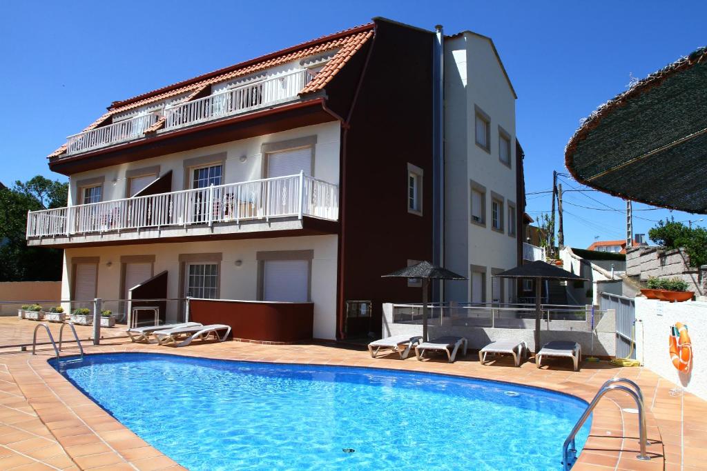 a house with a swimming pool in front of a building at Apartamentos Coral Do Mar I in Portonovo