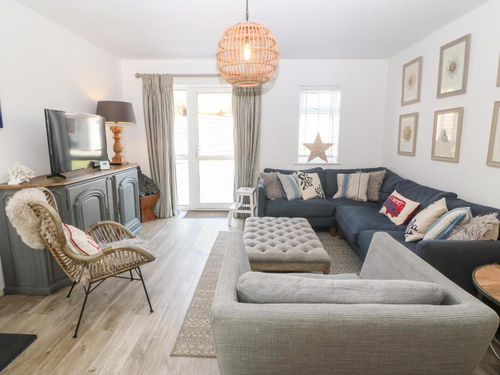 uma sala de estar com um sofá azul e uma televisão em Llwyn Onn em Pwllheli