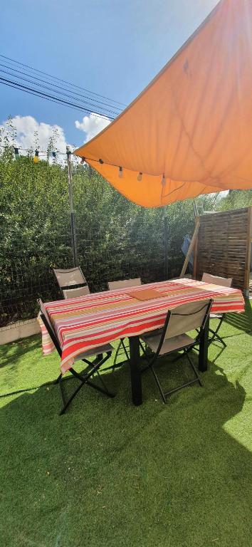 a picnic table with an umbrella on the grass at Appartement 2 chambres in Le Born
