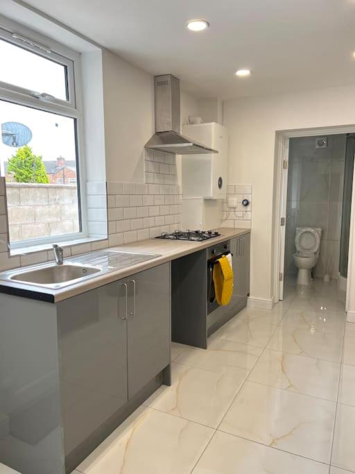 a white kitchen with a sink and a stove at Catherine 5 bedroom house in Crewe