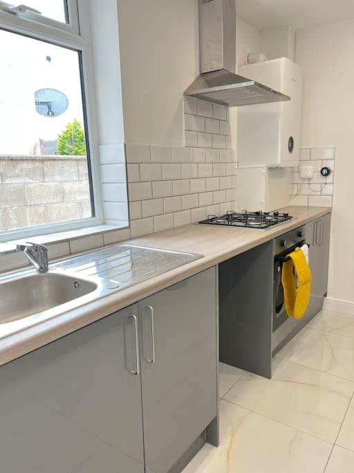 a white kitchen with a sink and a stove at Catherine 5 bedroom house in Crewe