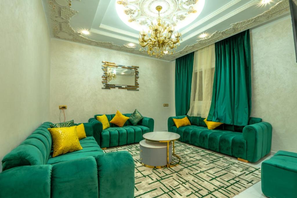 a living room with green couches and a chandelier at Laura Residence in Bouznika