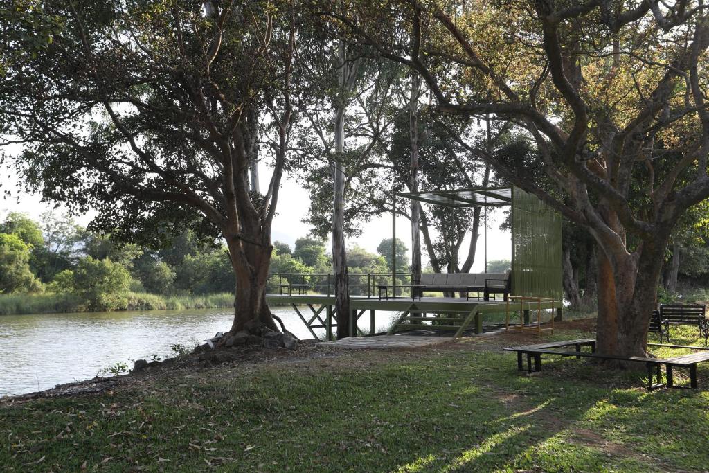 a park with a bench and trees next to a river at Golden Fields Resort in Mulshi