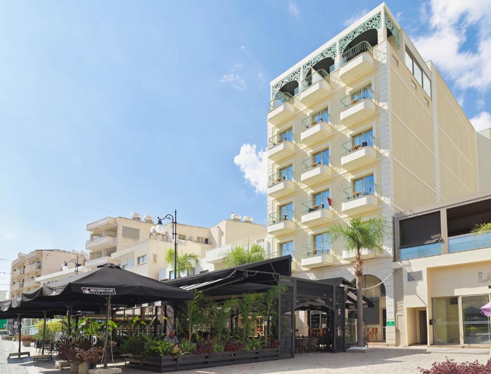 a large building with umbrellas in front of it at Leonardo Boutique Hotel Larnaca in Larnaca