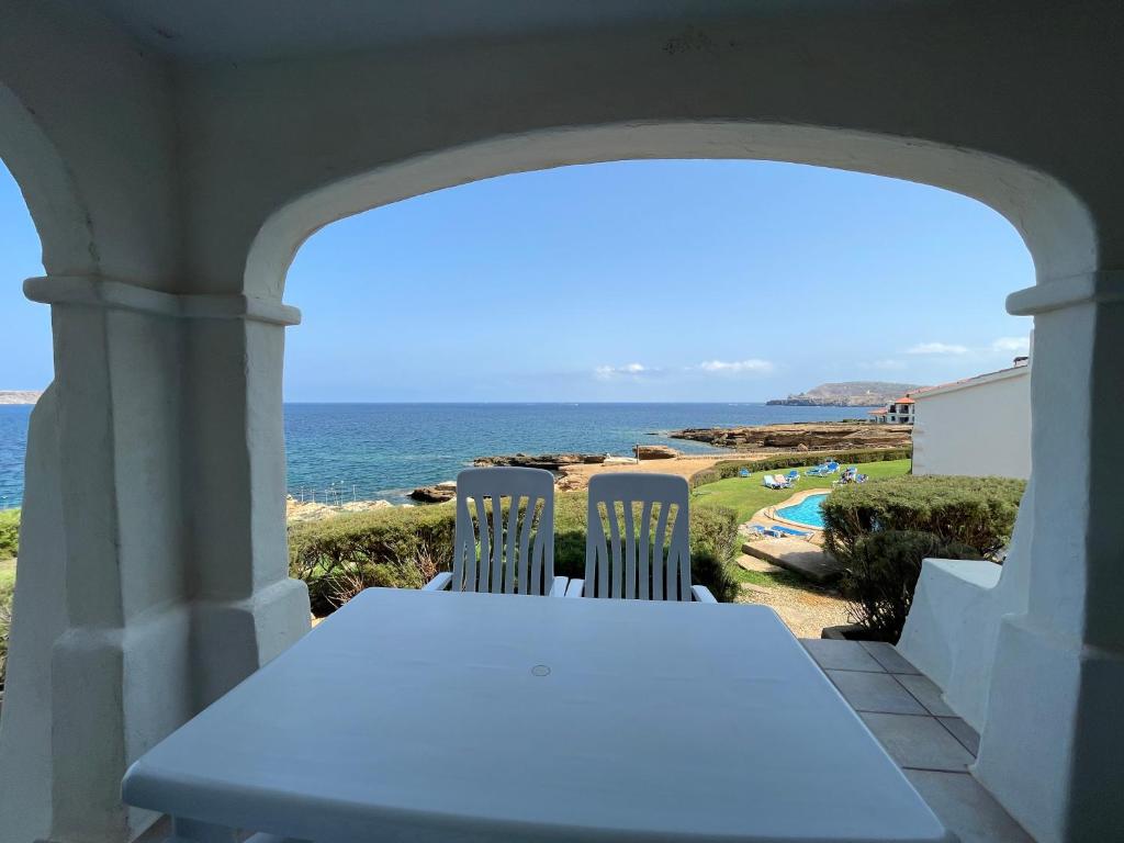 a table and two chairs on a porch looking out at the ocean at BERGANTIN 109 by SOM Menorca in Fornells