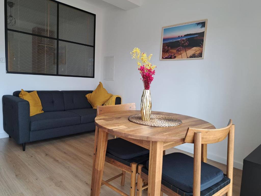 a living room with a table with a vase of flowers on it at Appartement proche plage hendaye in Hendaye
