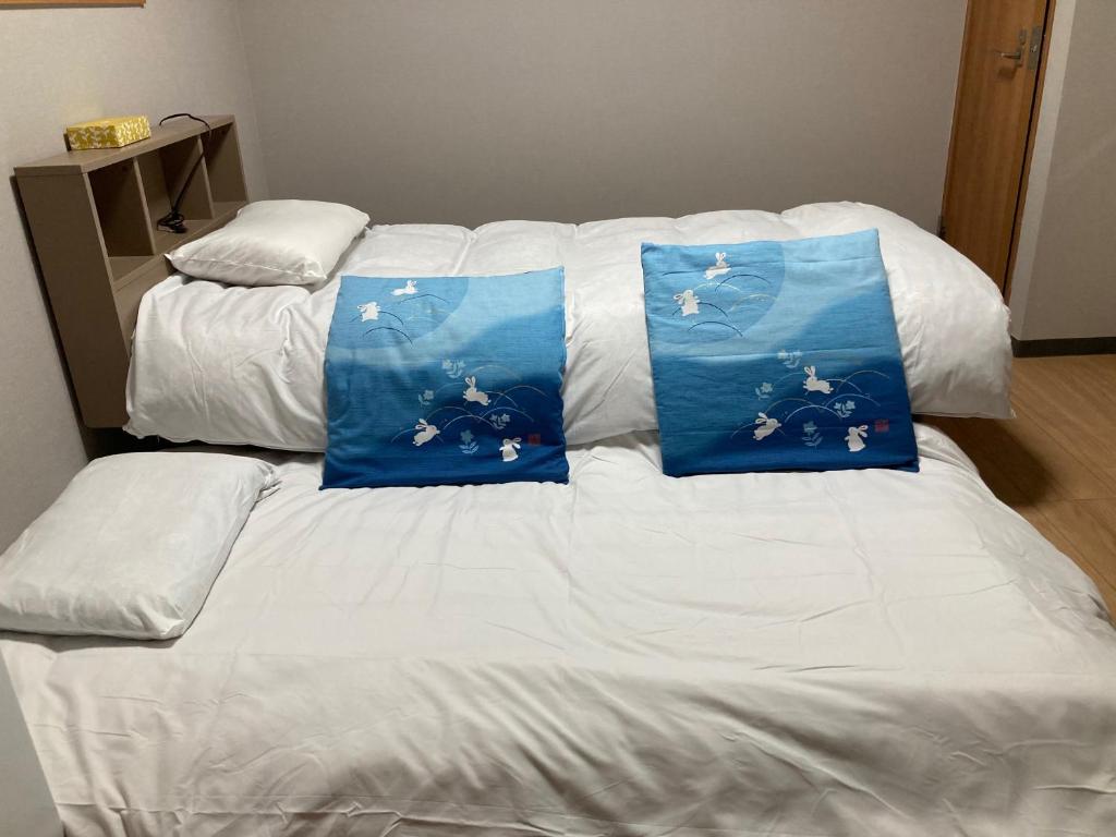 uma cama branca com duas almofadas azuis em Sky Tree INN (晴樹宿）stay ASAKUSA em Tóquio