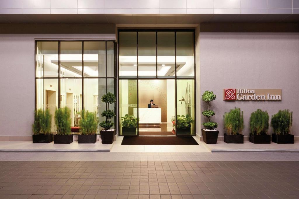 Hilton Garden Inn Puchong في بوتشونغ: لوبي فيه نباتات خزف في مبنى