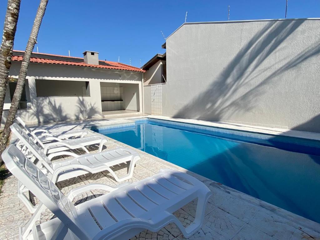 um grupo de cadeiras brancas e uma piscina em Linda Casa com Piscina em Marília