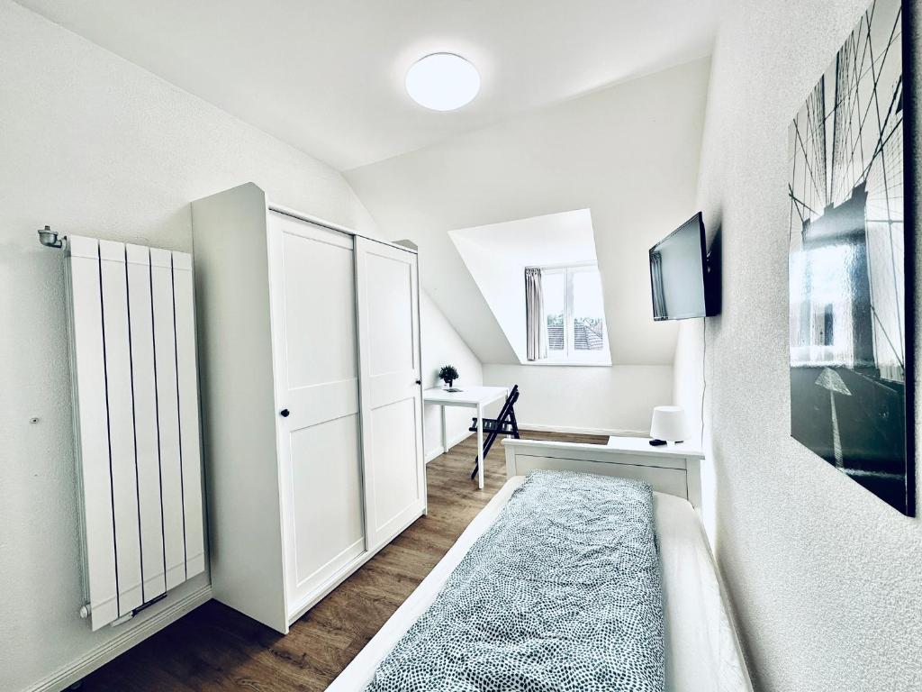 a white bedroom with a bed and a desk at Monteurzimmer ZIMMERzuVERMIETEN in Lengnau BE in Lengnau