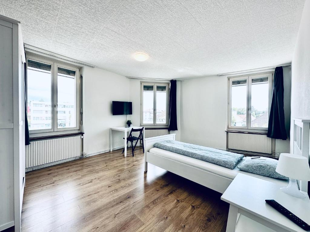 Un dormitorio con cama, escritorio y ventanas en Monteurzimmer - Worker's accommodation - ZIMMERzuVERMIETEN in Lengnau BE, en Lengnau
