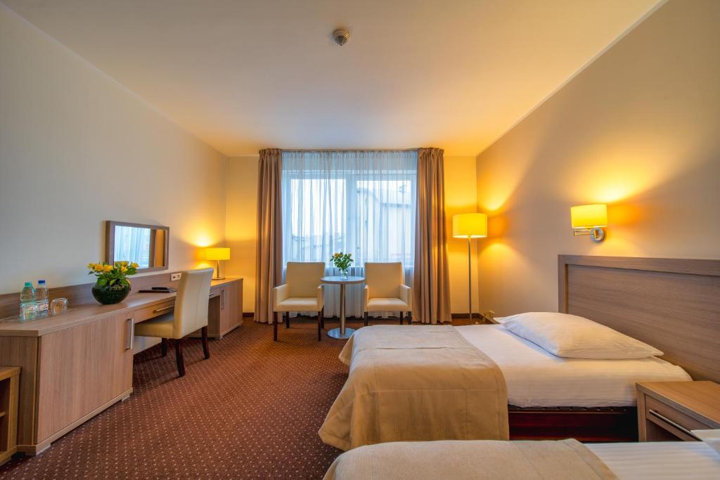 a hotel room with two beds and a desk at Hotel Gromada Arka Lux in Koszalin