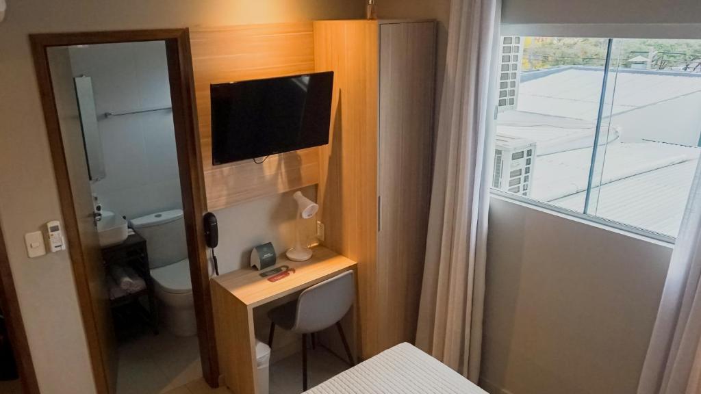 uma casa de banho com uma secretária, uma televisão e uma janela em Mako´s Hotel em Encarnación