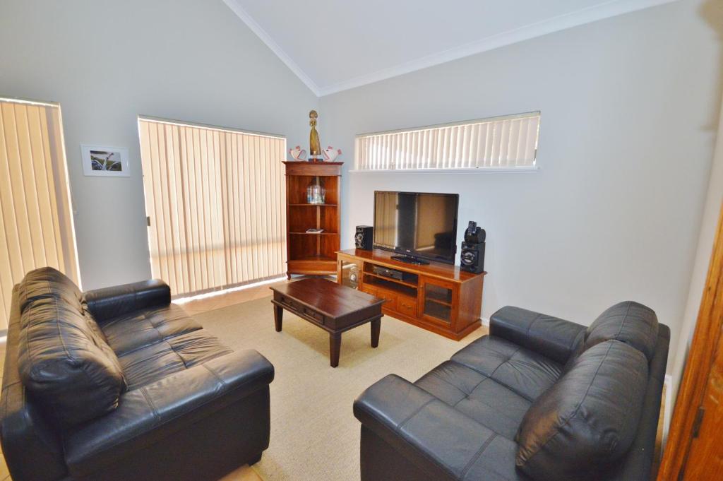 a living room with a leather couch and a television at Kalbarri Getaway - Kalbarri WA in Kalbarri