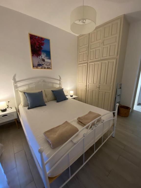 um quarto com uma cama branca e almofadas azuis em Wee Hoose em Skiathos Town