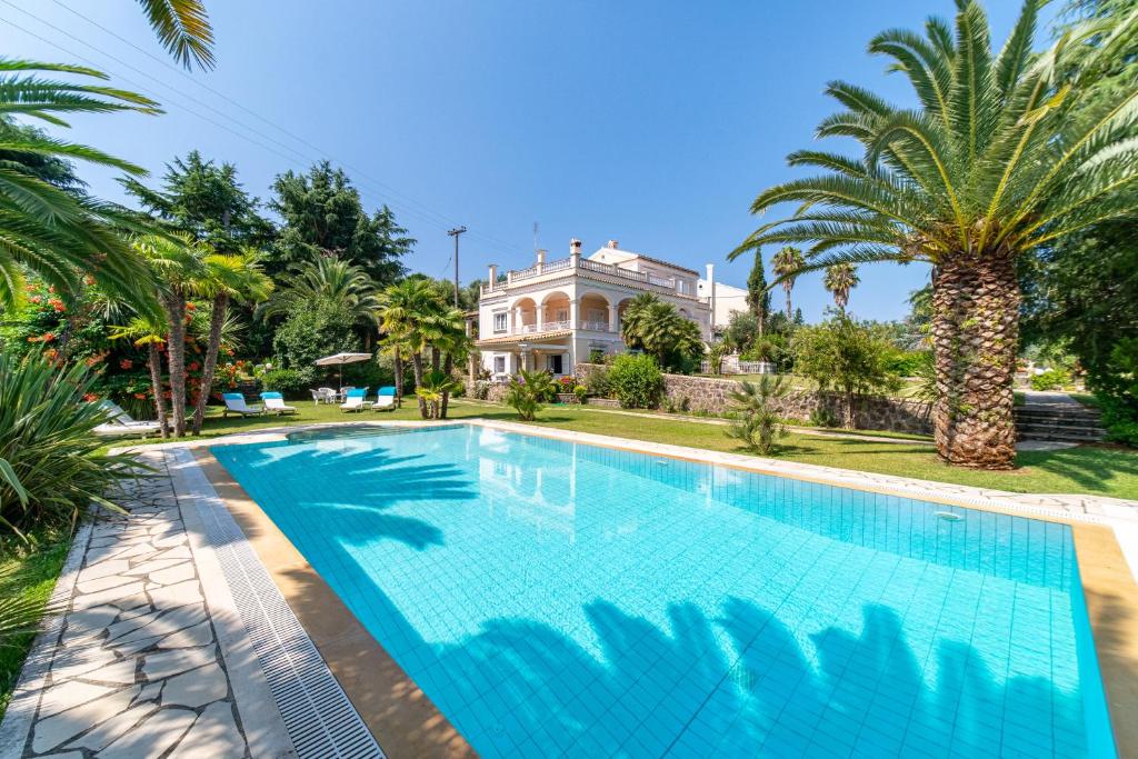 una piscina frente a una casa con palmeras en Villa Atalanti, en Gouvia