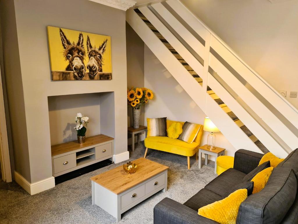 a living room with yellow furniture and a staircase at Tower Views 2 Bedroom House with Private Parking in Blackpool