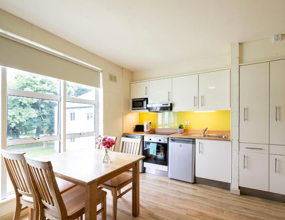 a kitchen with a wooden table with chairs and a table and a window at Corrib Village Apartments University of Galway in Galway