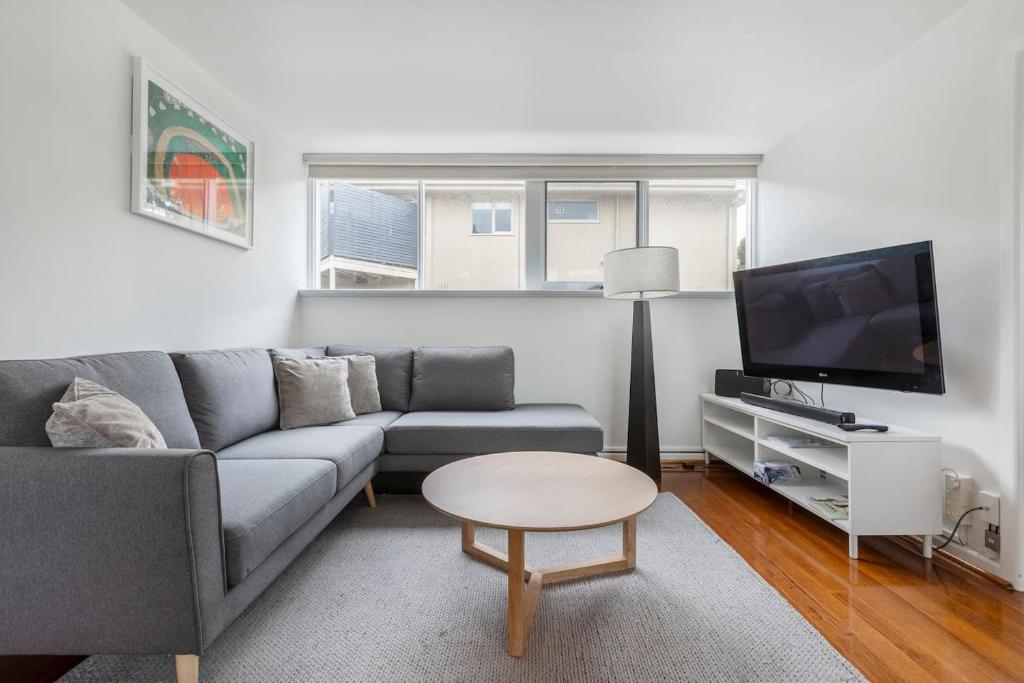 a living room with a couch and a tv at Bright and Modern Space with a Balcony and Parking in Melbourne