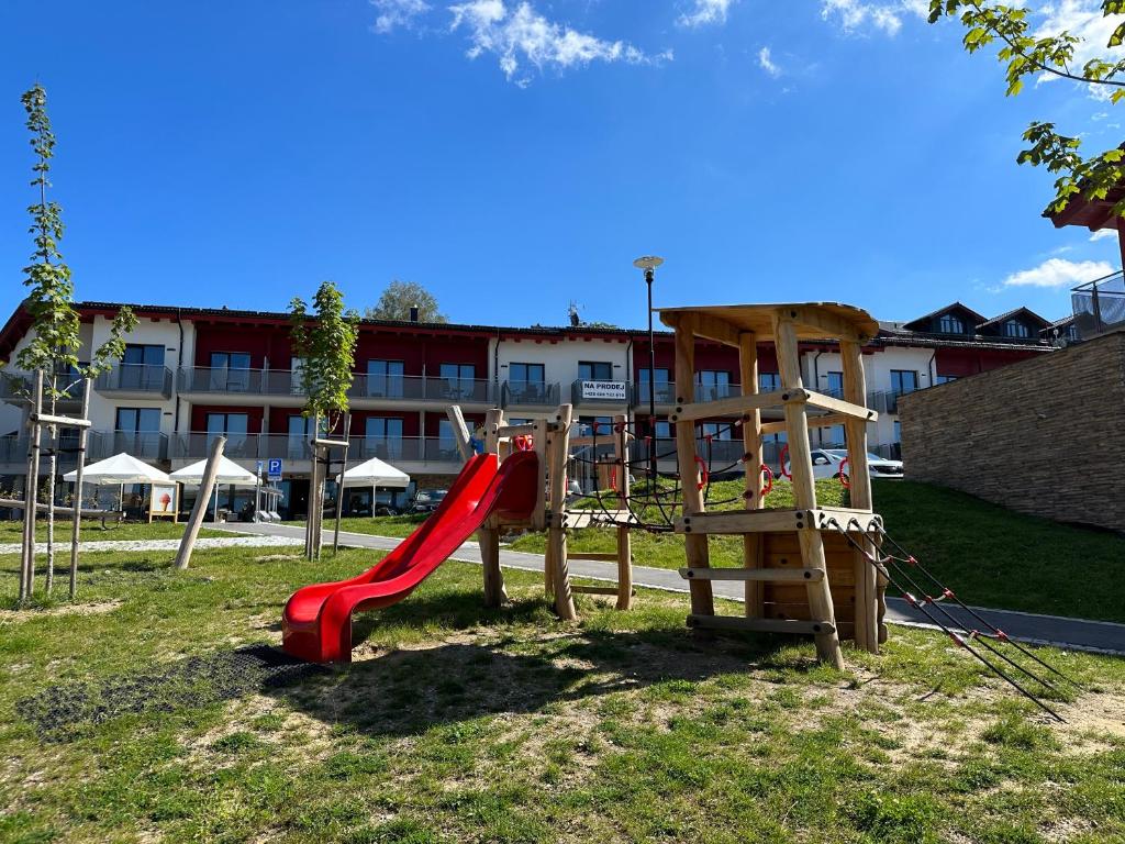 un parque infantil con un tobogán rojo y una escalera en Apartmán Monika, en Lipno nad Vltavou