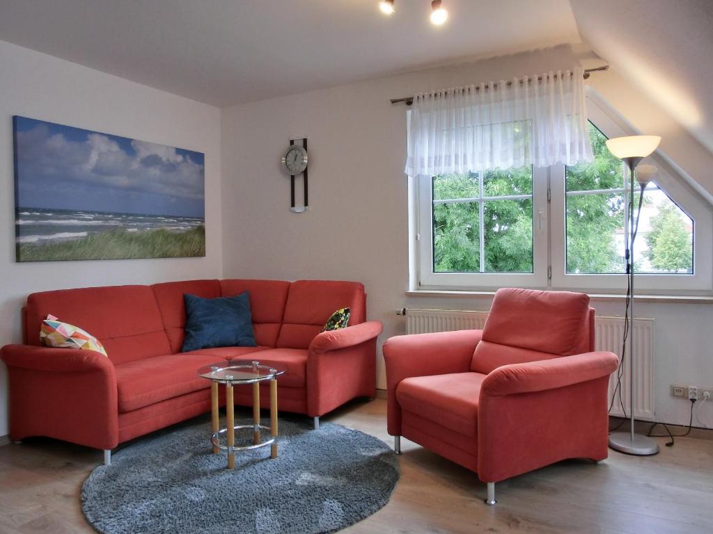 a living room with a red couch and two chairs at Ferienwohnung P3 in Graal-Müritz