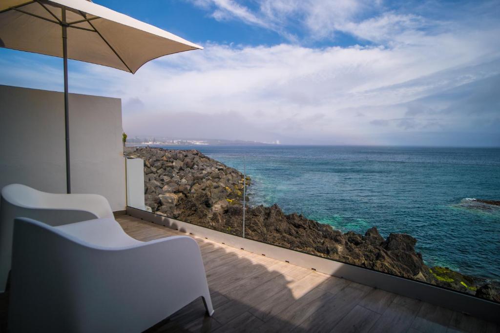 uma vista para o oceano a partir de uma varanda com um guarda-sol em Home at Azores - Islet House em Ponta Delgada