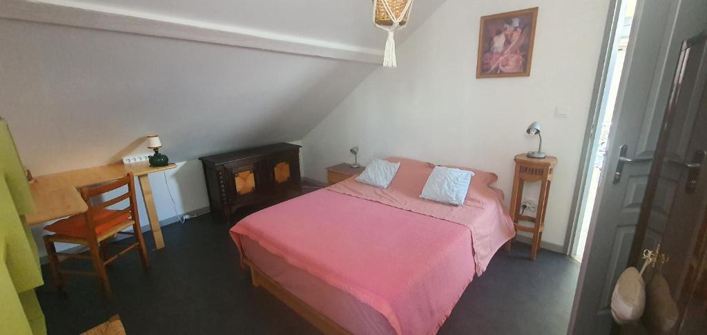 um pequeno quarto com uma cama rosa e uma mesa em Cramiland - Chambre d'hôte chez nous em Montbéliard