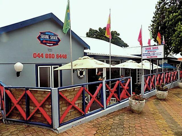 a restaurant with umbrellas in front of a building at Shark shacks in Mossel Bay