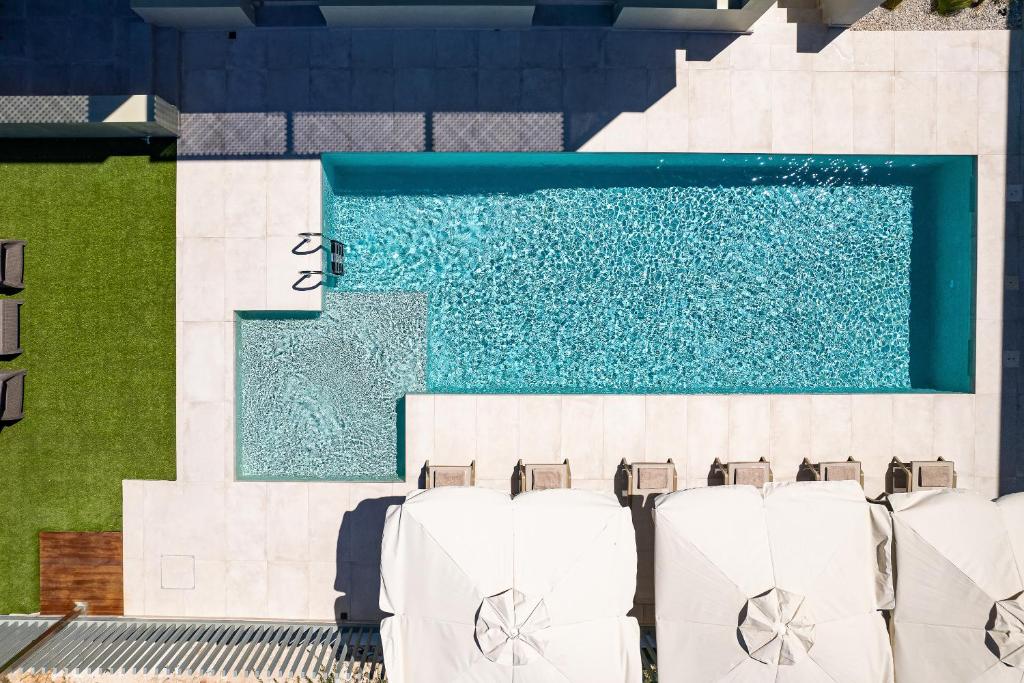 a pool with white chairs next to a swimming pool at Heliades Residence in Kounoupidhianá