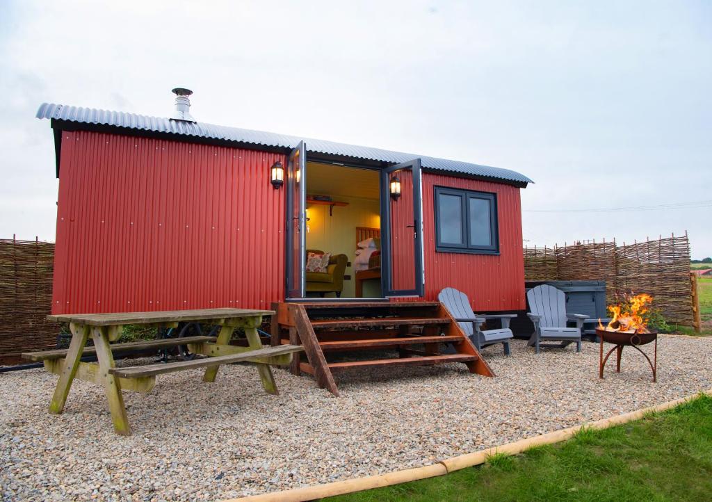 a red tiny house with a fire in the yard at The Gambo Shepherd's Hut in Kidwelly