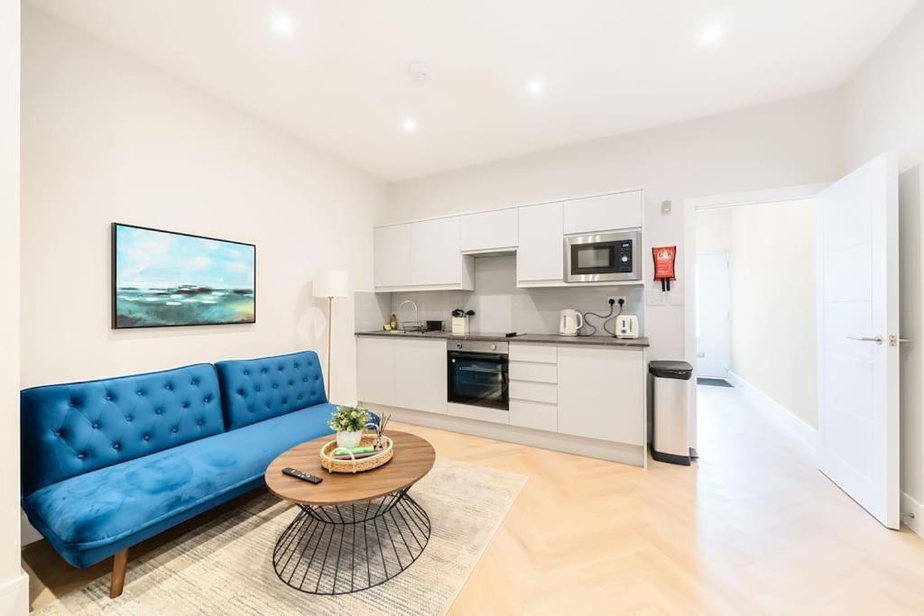 uma sala de estar com um sofá azul e uma mesa em The Solo Haven 20 Min to Central em Londres