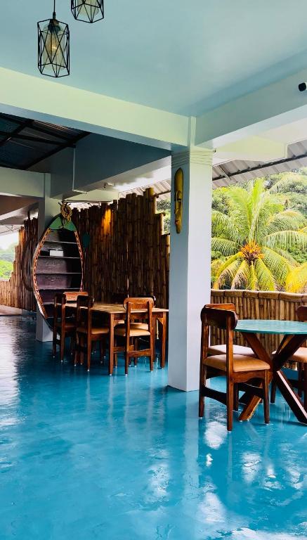 a restaurant with blue floors and wooden tables and chairs at Bhūma in Havelock Island