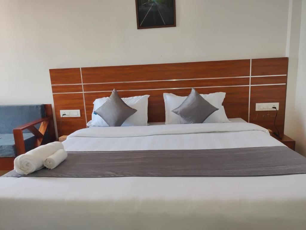 1 dormitorio con 1 cama blanca grande y cabecero de madera en Burj Munnar en Anachal