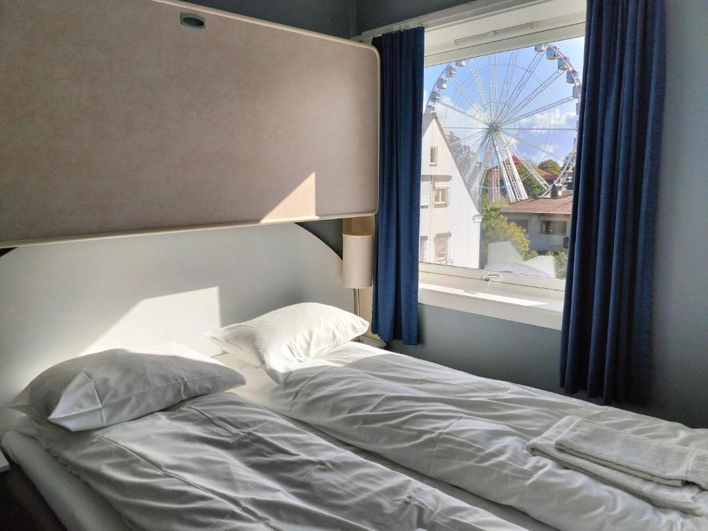 a bed in a bedroom with a window and a wheel at Sjøgløtt Gjestgiveri in Kristiansand