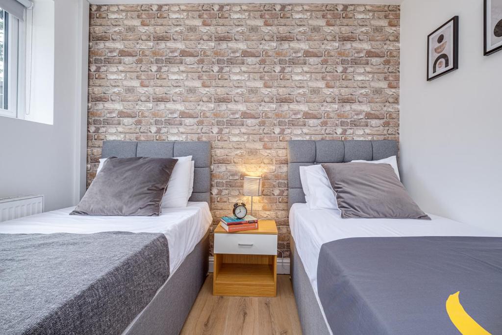 two beds in a room with a brick wall at Alpha House by Night Stay: Contractors Sleeps 8 in Birmingham
